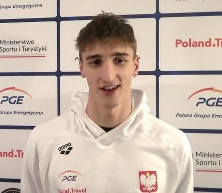 Ksawery Masiuk podczas treningu pływackiego, dynamiczne ujęcie w basenie, z rozpryskującą się wodą, ukazujące determinację i wysiłek.