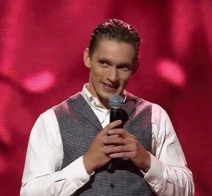 Filip Gurłacz uśmiecha się, witając się z fanami na wydarzeniu publicznym.