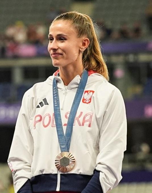 Natalia Bukowiecka na bieżni, z medalem, symbolizująca sukcesy w karierze lekkoatletycznej.