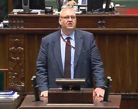 Bogdan Roman Święczkowski w trakcie wystąpienia, z silnym wyrazem twarzy, symbolizującym jego bezkompromisowy styl zarządzania.