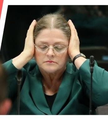 Krystyna Pawłowicz podczas publicznego wystąpienia, z charakterystycznym dla niej wyrazem twarzy i gestykulacją, oddającym jej stanowczy charakter.
