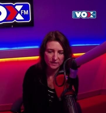 Renata Dąbkowska na scenie z zespołem, śpiewająca do mikrofonu, z widocznymi instrumentami i dynamicznym oświetleniem.