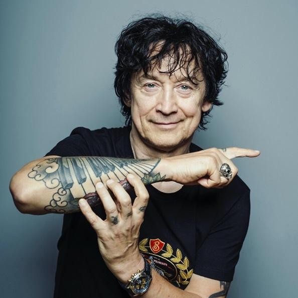 Jan Borysewicz na scenie podczas koncertu Lady Pank, energicznie grający na gitarze elektrycznej, z dynamicznym oświetleniem.