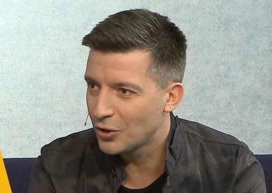 Michał Cessanis podczas prelekcji o podróżach, z widownią i slajdami w tle.