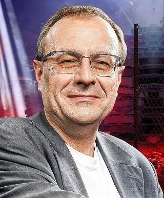 Antoni Dudek podczas wykładu lub prezentacji, dynamicznie gestykulujący, co podkreśla jego charyzmę i wiedzę.