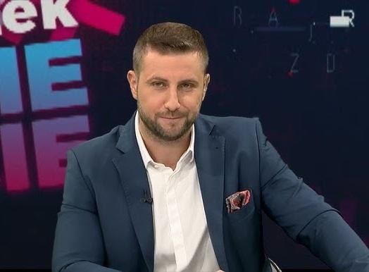 Miłosz Kłeczek podczas ostrej debaty w studiu telewizyjnym, gestykulujący z determinacją.