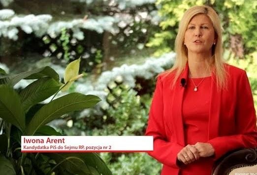 Iwona Arent podczas wystąpienia, gestykulująca, na tle sugerującym obrady sejmowe, ukazująca jej zaangażowanie i pasję polityczną.