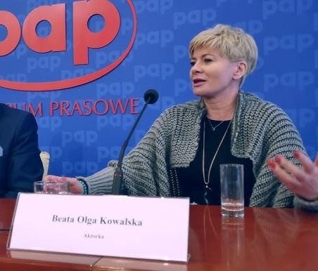 Dynamiczny portret Beaty Olgi Kowalskiej, ukazujący jej energię i wszechstronność artystyczną, z elementami nawiązującymi do jej różnorodnych ról teatralnych i telewizyjnych.