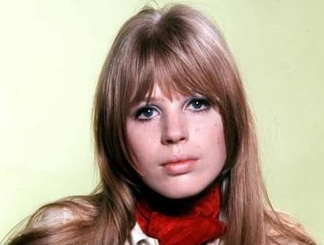 Marianne Faithfull na scenie podczas występu, z mikrofonem w dłoni, uchwycona w dynamicznej pozie, oddającej jej sceniczną energię i emocje.